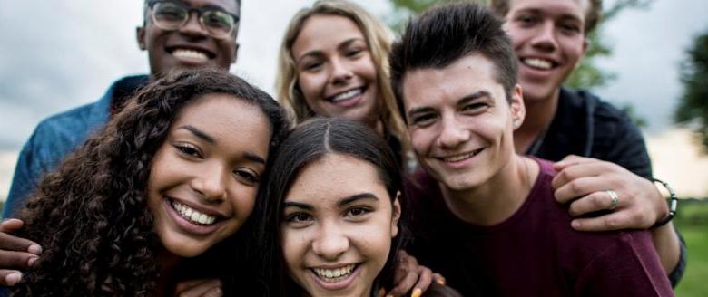 Grupo de adolescentes multiculturales sonriendo y mirando a la cámara