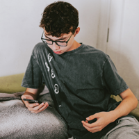 一名拉丁裔青少年在电话会议时盯着手机屏幕的照片