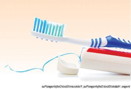 Foto de un cepillo de dientes y pasta de dientes sobre un fondo degradado de color naranja claro