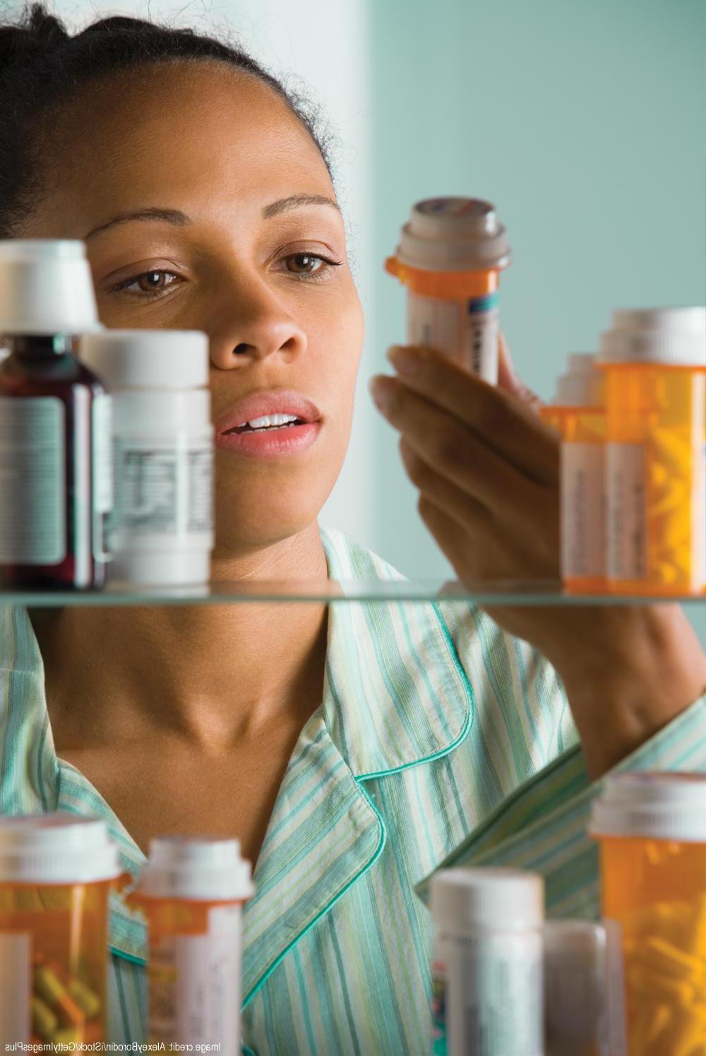 photo of woman inspecting medicines in cabinet
